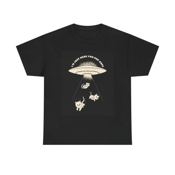 T-shirt preta com ilustração de um OVNI e três animais sob um feixe de luz, texto "I must here for the cake" no topo.