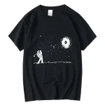 T-shirt preta com um padrão de astronauta jogando no espaço, observando uma galáxia e estrelas, design minimalista e artístico.