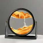 Vase décoratif en forme de cercle avec sable coloré simulant un paysage géologique, posé sur un support noir. Idéal pour la décoration scientifique ou moderne.