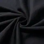 Tissu noir enroulé, texture douce et élégante, idéal pour la couture ou la décoration intérieure. Parfait pour des projets créatifs ou des vêtements sophistiqués.