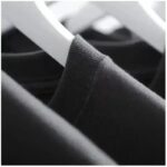 T-shirt noir en coton suspendu sur un cintre, vue rapprochée, fond flou.