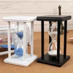 Ampulheta em madeira preta e branca com vidro transparente, decoração de estilo científico, ideal para uma loja ou espaço de decoração temática científica.