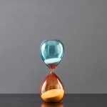 Lâmpada de vidro com areia colorida azul e laranja, decoração científica elegante, ideal para um interior moderno ou um espaço de escritório inspirador.