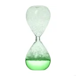 Ampulheta de vidro com areia verde e branca, símbolo do tempo que passa, ideal para decoração científica ou como objeto de coleção.