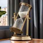 Ampulheta decorativa em latão com areia branca, ideal para decoração interior ou como objeto de coleção científica.