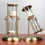 Ampulheta decorativa em metal dourado, ideal para decoração interior ou como objeto de coleção. Design elegante com duas ampulhetas, trazendo um toque científico e sofisticado.