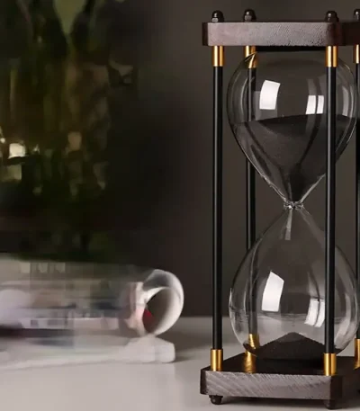 Ampulheta científica em vidro com estrutura de madeira e elementos metálicos dourados, ideal para decoração de escritório ou prateleira com estilo industrial ou científico.
