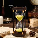 Ampulheta decorativa em madeira e vidro, mede 24 cm de altura e 9,5 cm de largura, perfeita para decoração de escritório ou interior.