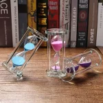 Relógios de areia em vidro com pós coloridos rosa, azul e roxo, usados como decoração científica ou para a medição do tempo.