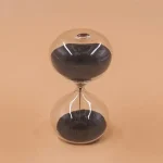 Ampulheta em vidro com areia preta e transparente, design elegante e moderno, perfeita para decoração científica ou como objeto de coleção.