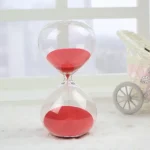 Ampulheta em vidro transparente com areia vermelha, decoração científica elegante para escritório ou casa.