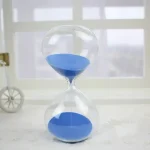Ampulheta de laboratório com areia azul, símbolo da medição do tempo, ideal para decoração científica ou educativa.