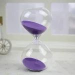 Ampulheta científica com areia roxa, símbolo da medição do tempo, ideal para decoração de escritório ou estudos, trazendo um toque científico e elegante.