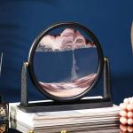 Objeto científico em vidro com estrutura preta, relógio de areia em movimento, decoração de ciência, ideal para um escritório ou prateleira.