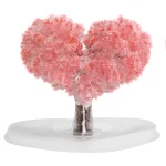 Escultura artística representando um coração formado por uma árvore de algodão rosa, colocada sobre uma base branca, evocando suavidade e ternura.
