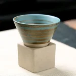 Taça em cerâmica com padrões geométricos, colocada sobre um pedestal de concreto, ideal para decoração científica ou para uma coleção de objetos decorativos.