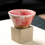 Pequeno pote em cerâmica vermelha e branca colocado sobre uma base de concreto, ideal para decoração científica ou botânica.