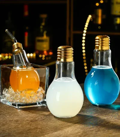 Três lâmpadas decorativas preenchidas com líquidos coloridos (laranja, branco, azul) sobre uma mesa de madeira, ambiente acolhedor e moderno.