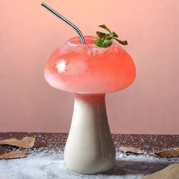Copo em forma de cogumelo contendo um cocktail rosa com um ramo de hortelã, decorativo e original.