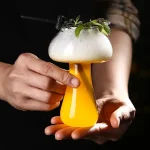 Copo de cocktail científico com espuma, guarnição verde e decoração de laboratório, perfeito para uma decoração original ou evento temático científico.