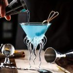 Vaso de vidro transparente com suporte em forma de tentáculos, ideal para decoração científica ou moderna.