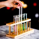 Teste de laboratório com tubos de ensaio coloridos em um suporte de madeira.