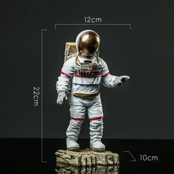 Figura de astronauta em miniatura com capacete dourado, medindo 22 cm de altura, 12 cm de largura e 10 cm de profundidade, colocada sobre uma base rochosa, ideal para decoração científica.