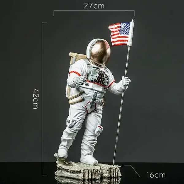 Figura de astronauta com bandeira americana, altura de 42 cm, dimensões 27x16 cm, representando um explorador espacial em traje completo, em pé sobre uma base rochosa.