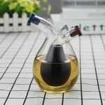 Vaso de laboratório em vidro contendo um líquido preto, com dois tubos de vidro inclinados, usado para experiências científicas ou decorativas.