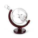 Bússola em vidro representando um globo terrestre com um barco em miniatura no interior, colocada sobre um suporte de madeira. Ideal para decoração científica ou como objeto de coleção.