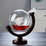 Globo de vidro contendo um líquido vermelho e um objeto científico, colocado sobre um suporte de madeira, decorativo e educativo.