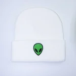 Boné branco com logotipo de alienígena verde e preto, estilo streetwear moderno.
