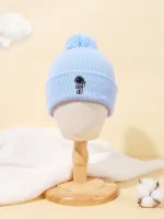 Gorro de lã azul claro com um pequeno personagem científico bordado, adornado com um pompom no topo. Perfeito para os amantes de ciência e moda de inverno.