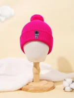 Gorro rosa de lã com emblema de astronauta, acessório quente e moderno para o inverno, apresentado em um manequim de madeira em um cenário suave e minimalista.