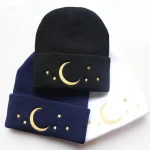 Gorro de lã com padrão de lua e estrelas douradas, disponível em preto, azul-marinho e branco. Perfeito para um estilo aconchegante e moderno, ideal para o inverno ou como acessório original.