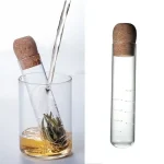 Pipeta de laboratório transformada em infusor de chá, contendo chá verde em infusão. Perfeito para uma decoração científica original ou uma experiência de degustação inovadora.