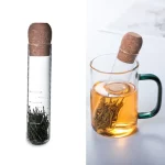 Infusor de chá em forma de tubo de ensaio com folhas de chá, ideal para decoração científica ou experiência de degustação de chá.