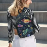 Mochila infantil com padrão de planetas e estrelas no espaço.