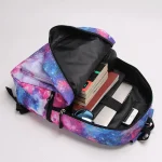 Mochila com padrão de galáxia, ideal para estudantes ou amantes da ciência, contendo livros, celular e outros acessórios.