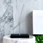 Objeto científico em decoração minimalista com tubos de metal e base preta.