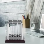 Pêndulo de Newton clássico com suporte de madeira, ideal para decoração científica e aprendizado de física. Perfeito para um escritório ou sala de aula.