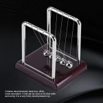 Pêndulo de Newton em metal brilhante com seis esferas suspensas, sobre base de madeira escura, ilustrando física e decoração científica.