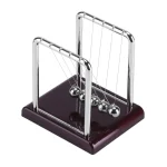 Pêndulo de Newton em metal brilhante com base de madeira escura, ilustrando a famosa experiência de física para demonstração da conservação de energia.