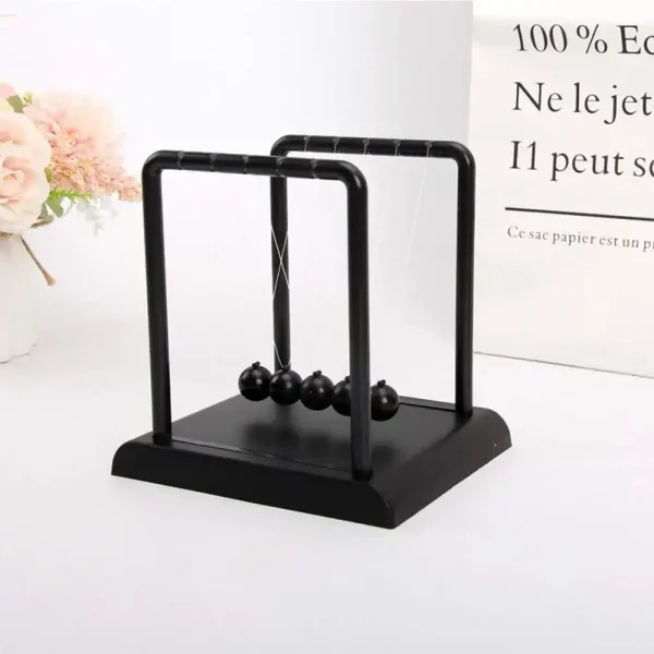 Pêndulo de Newton em metal preto com base em madeira, ideal para decoração científica ou educativa, trazendo um toque moderno e elegante ao seu interior.