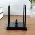 Pêndulo de Newton clássico com bolas de metal suspensas, ideal para decoração científica ou como objeto educativo em um escritório ou sala de aula.