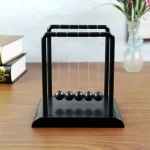 Bola de Newton em madeira preta, objeto de decoração científica, ideal para amantes de física e design moderno, para colocar em uma mesa ou prateleira.