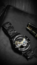 Relógio mecânico preto com movimento visível, pulseira em aço e detalhes dourados, aliando elegância e precisão para os amantes de ciência e design.