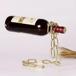 Garrafa de vinho suspensa com corrente de ouro e corda de juta, decoração original para um interior científico ou industrial.