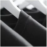 Camisola preta em algodão num cabide, vista em close-up.