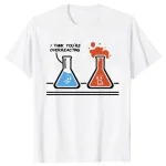 T-shirt branca com ilustração de dois frascos de laboratório, um azul e um vermelho, expressando uma reação química humorística com o texto "I think you're overreacting".